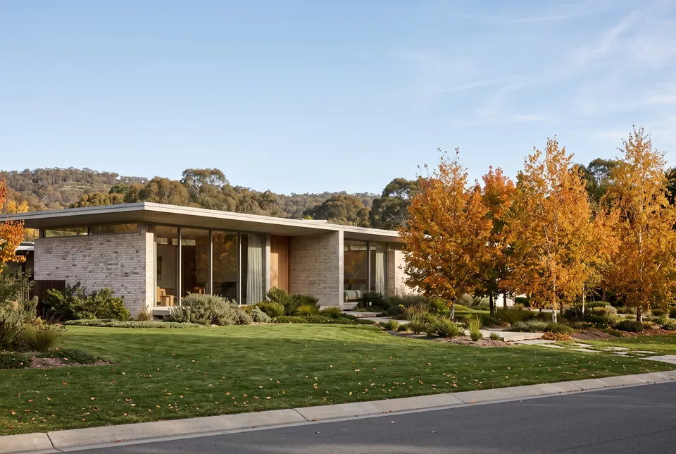 Long, low single-level Red Hill residence in pale brick and concrete with autumn trees